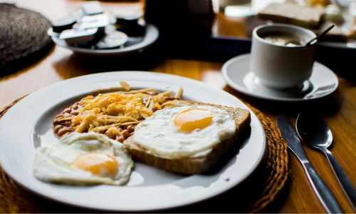 plate with beans and eggs on toast with grated cheese