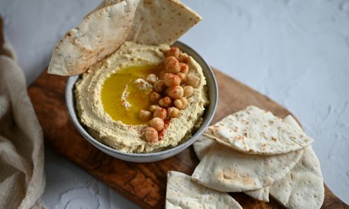 bowl of hummus with cut up pitta bread dipped in it