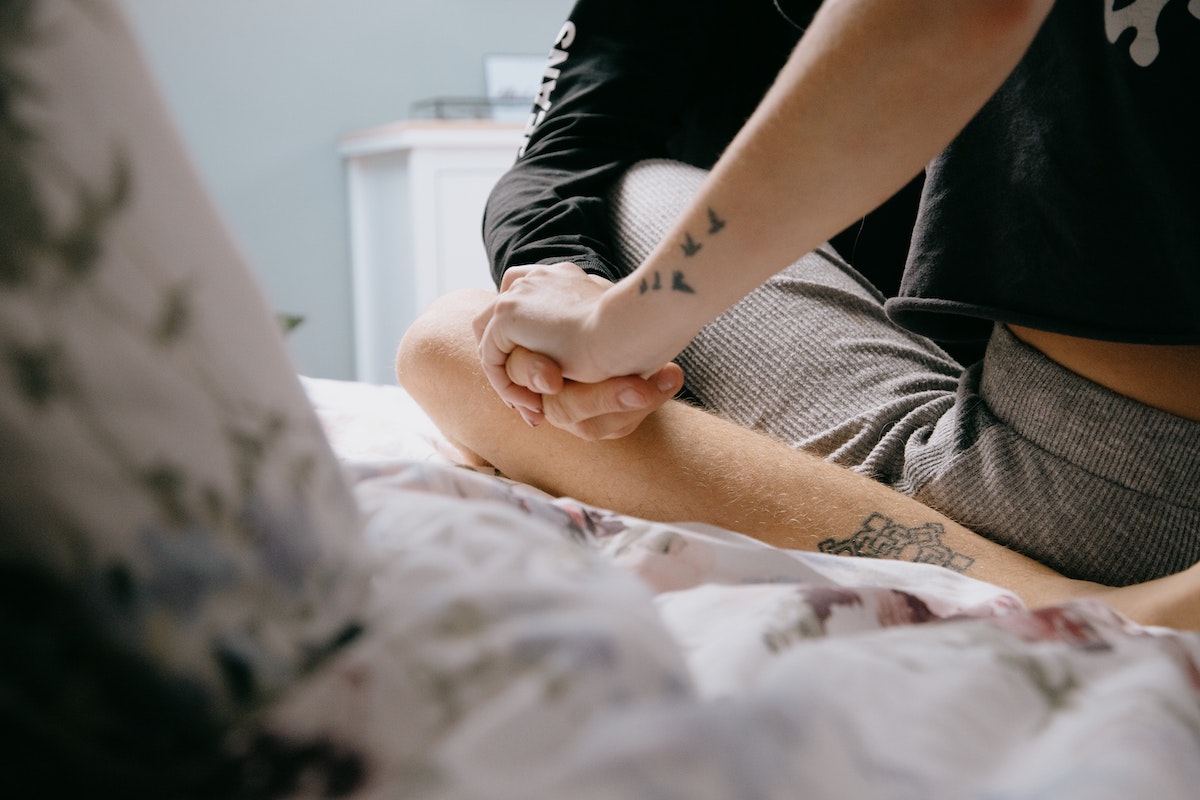 two people sat on down bed holding hands