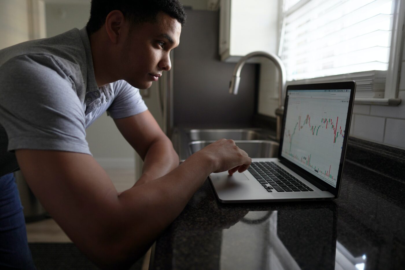 Student looking at a stock trading chart on his laptop