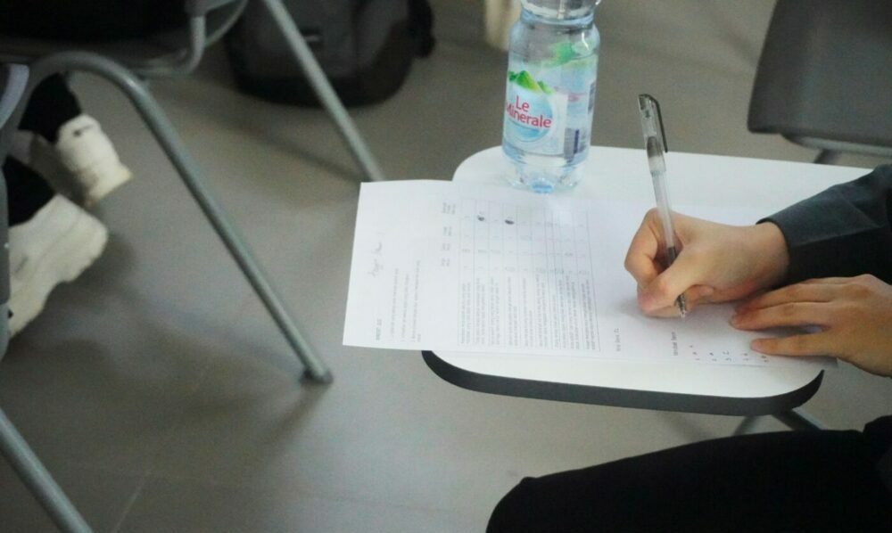 Person sat at table taking an exam with a water bottle on the table