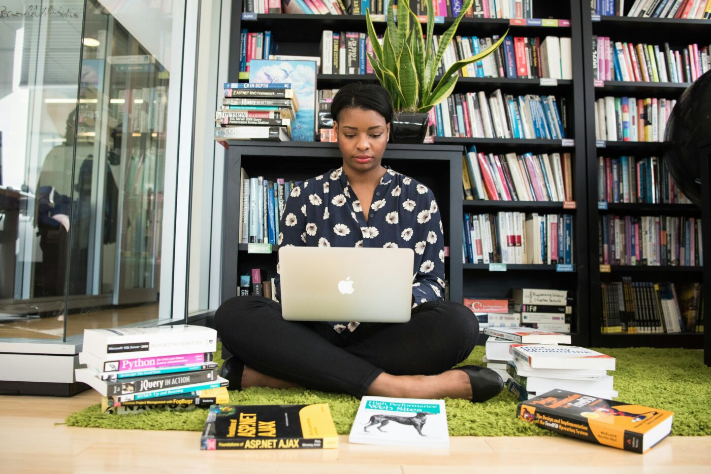 Woman sat on her laptop working surrounded by books