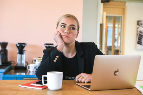 Blonde woman bored at laptop struggling to concentrate - studying with ADHD