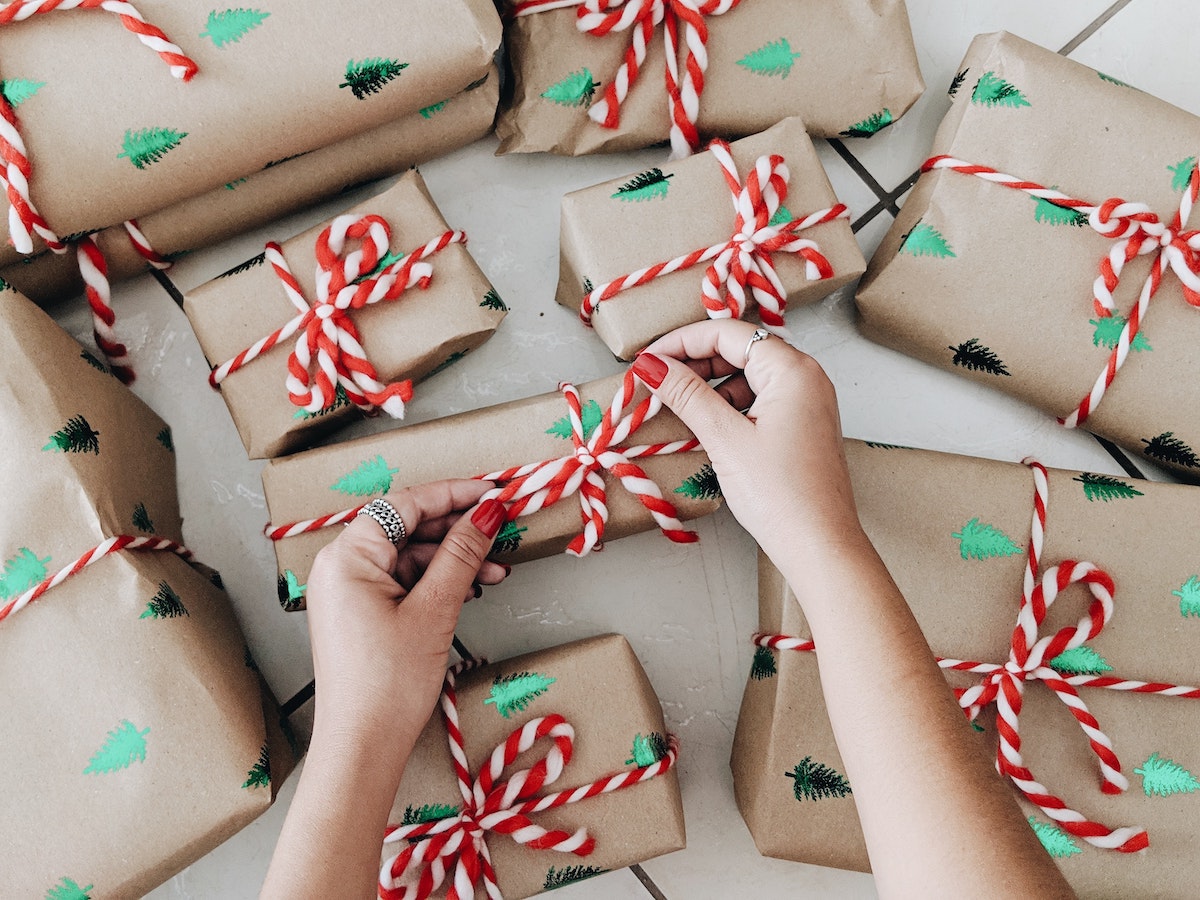 Christmas gifts being wrapped up by a hand wearing nail polish