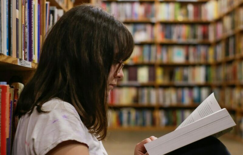 Woman sat on the floor in the library reading