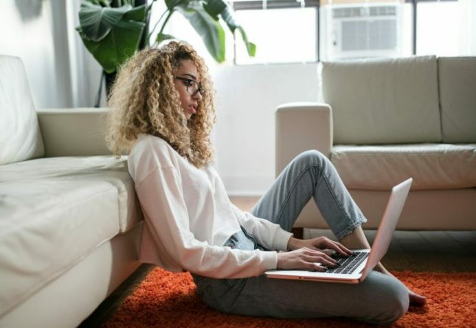 Woman sat on the floor with her laptop on her legs