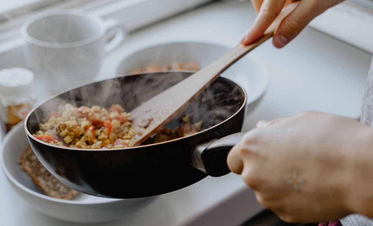 person frying tofu scrambled eggs - cheap student meals for one