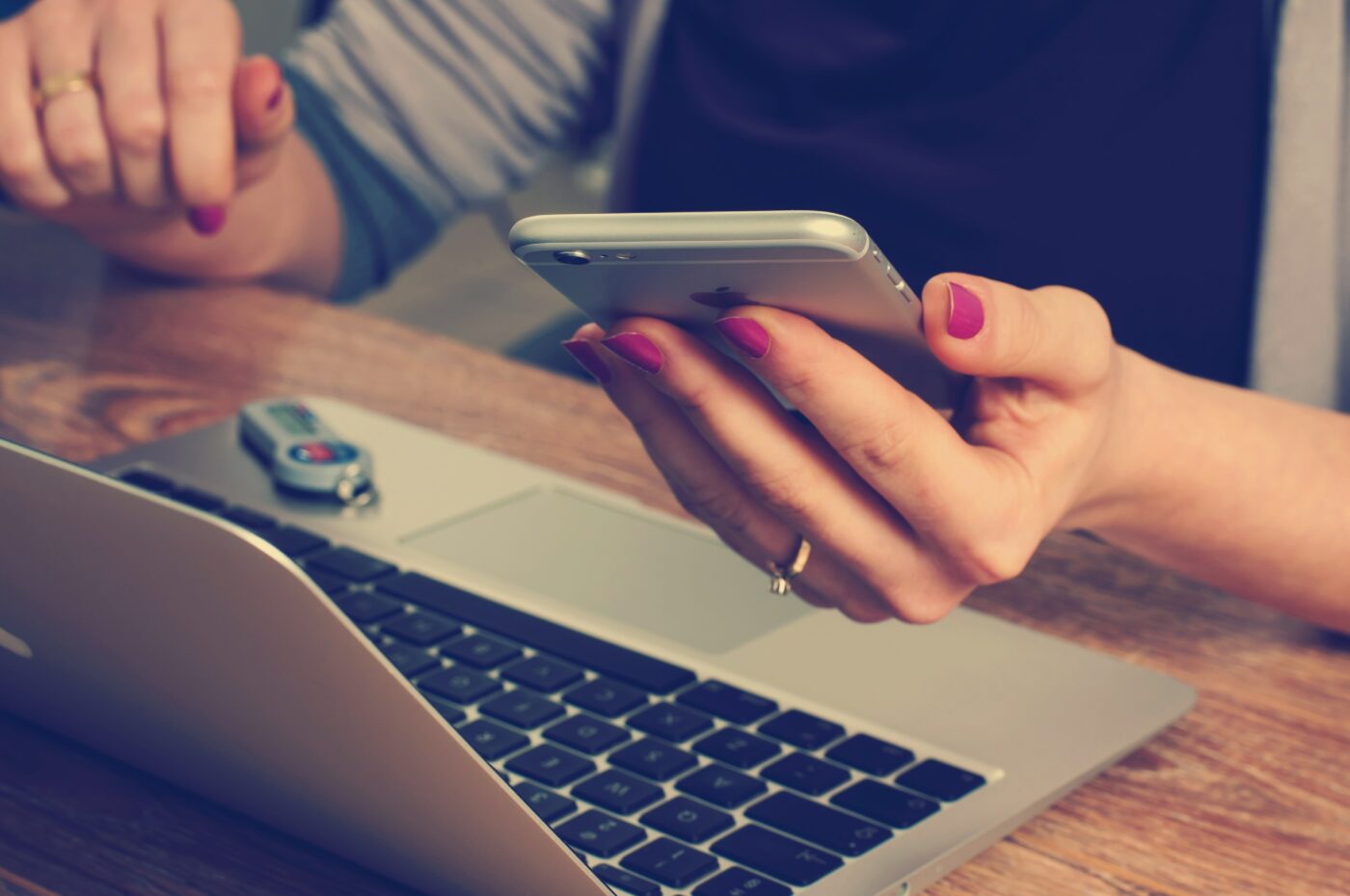 A picture of someone sitting at their laptop with their phone in their hands - student finance payment dates
