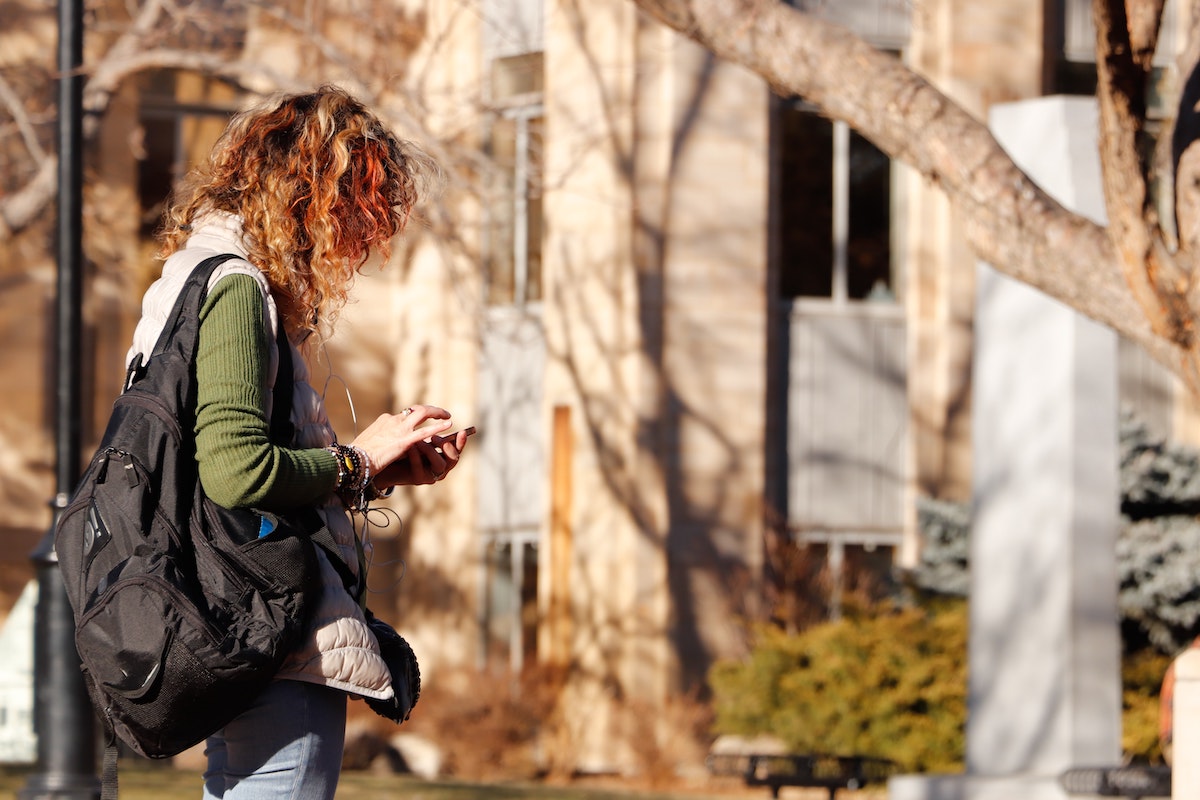 when to move into halls 1.jpg when do you move into uni accommodation - woman looking at phone on uni campus