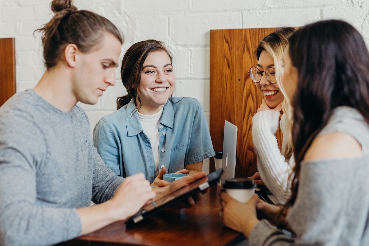 when to move into halls 2.jpg when do you move into uni accommodation - group of friends drinking coffee and on their laptops or phones