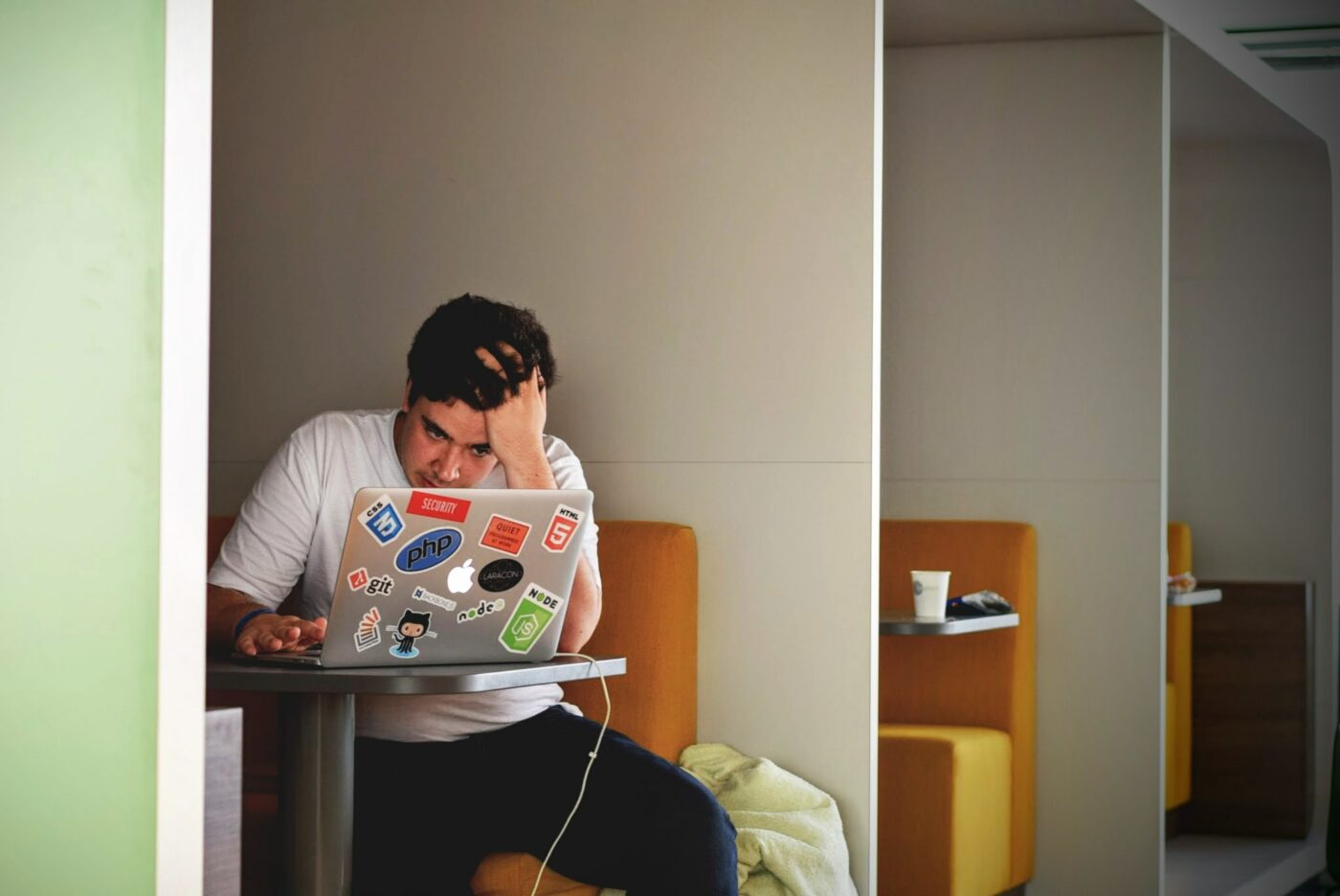 A male student sat at his laptop revising for his exams with his head in his hands