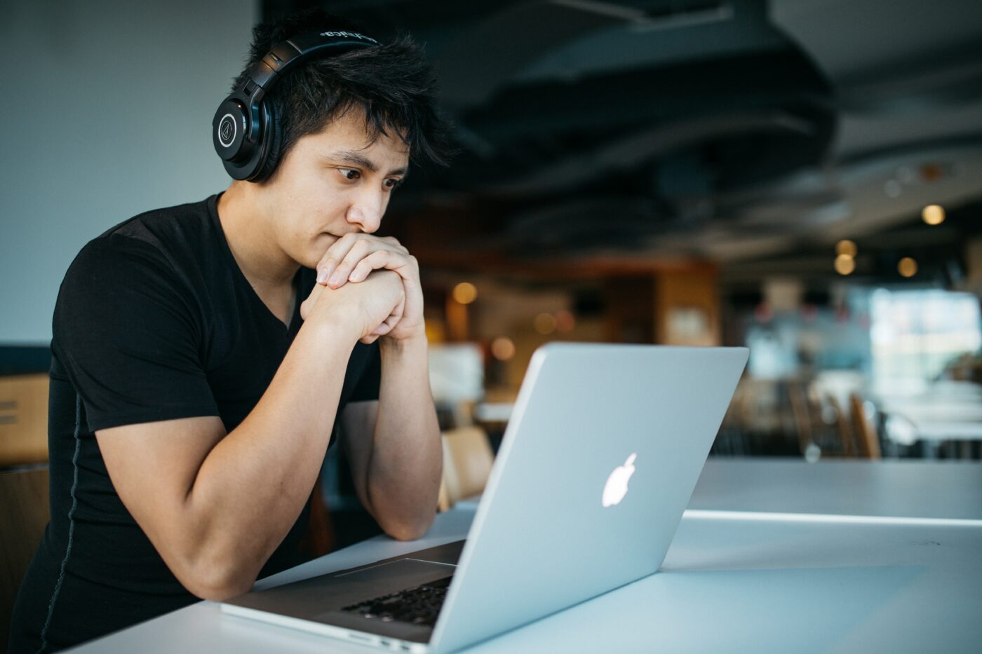 A man with headphones  on staring at his laptop screen